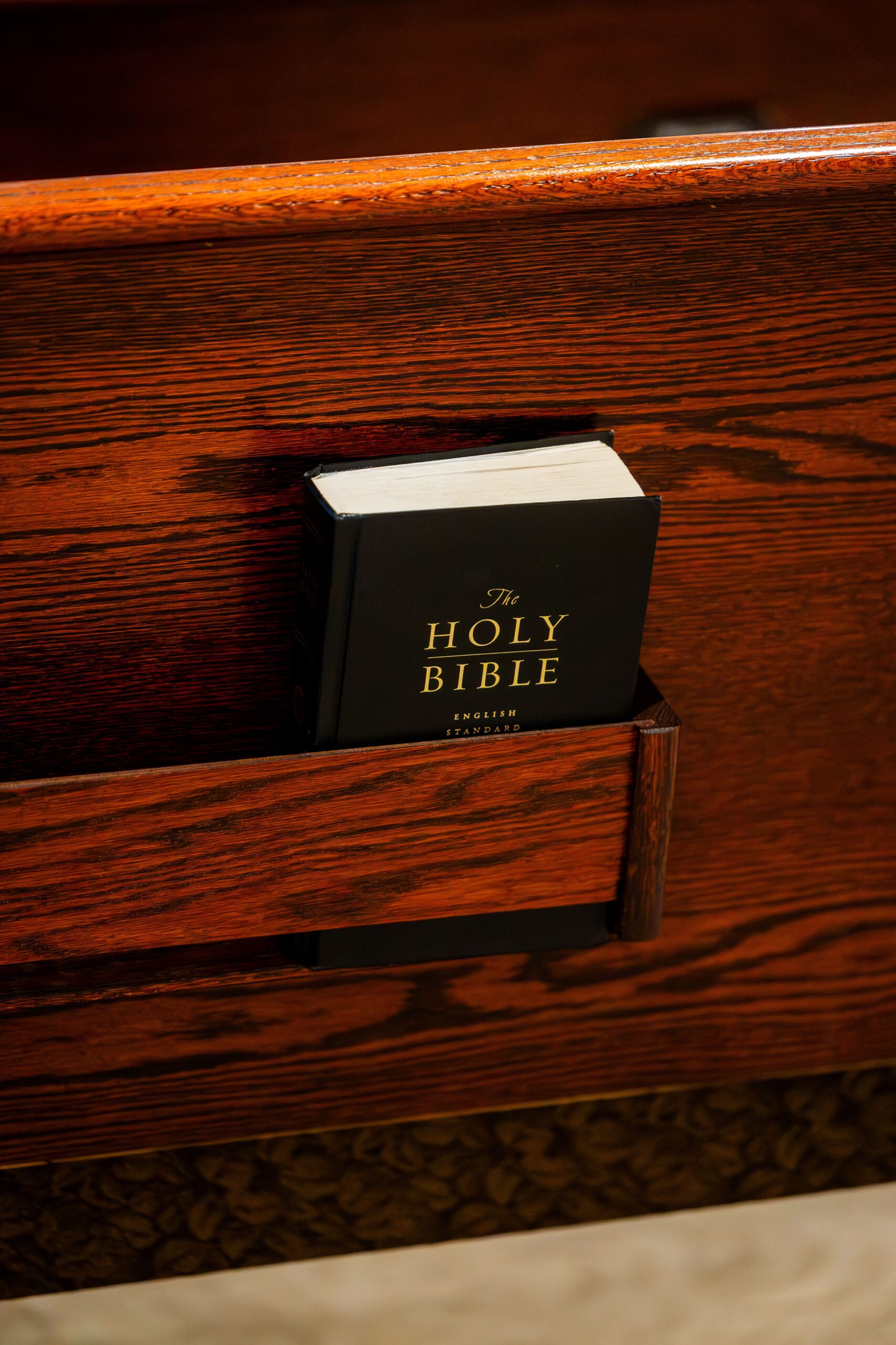 A Holy Bible resting in a church pew holder, symbolizing faith and spirituality.