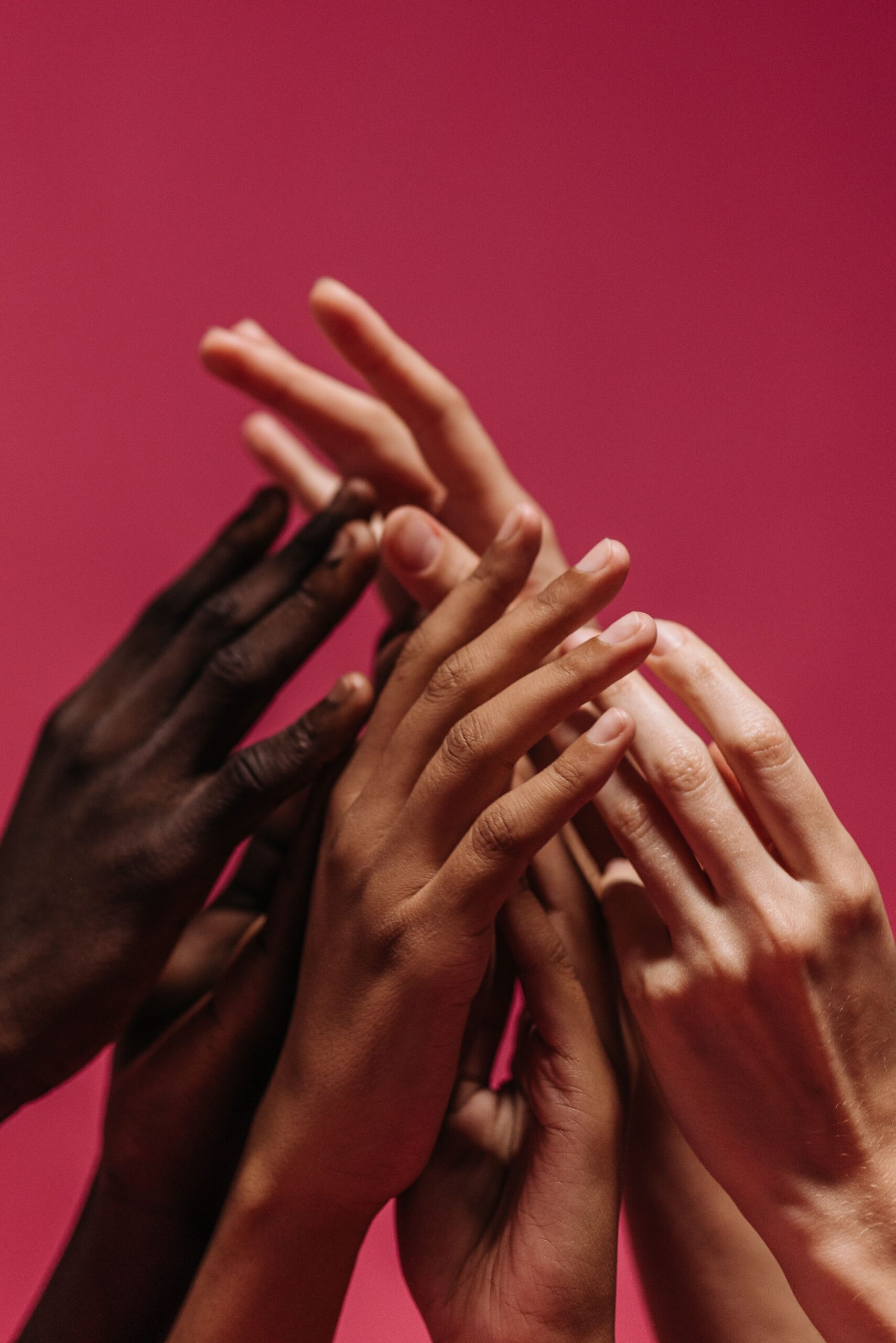 A close-up of diverse hands touching, symbolizing solidarity and unity on a red background.